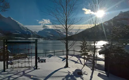 Uteområdet i Lakselvbukt barnehage en strålende vinterdag med sol, hav og fjell