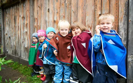 Seks barn ved gjerde med fargerike luhkka i Samisk barnehage 