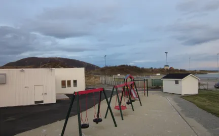 Sommarøy barnehage uteområde med husker og sandkasse en sommerdag