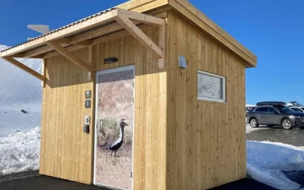 Slik ser et av Tromsø kommunes friluftstoalett ut. Her er toalettdøren utsmykket med fotografi av en fuggel.