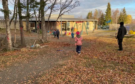 Workinnmarka barnehage uteområde med store trær og løv på bakken en sen høstdag