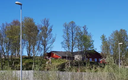 Ameliahaugen barnehage sett utenfra en fin sommerdag med trær og blå himmel