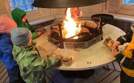 Norlandia Polarmåsen barnehage Fire barn som legger ved på bålet i grillhytta ved Norlandia Polarmåsen barnehage