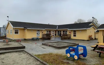 Uteområde med sandkasse, benker og bord i Polarhagen barnehage