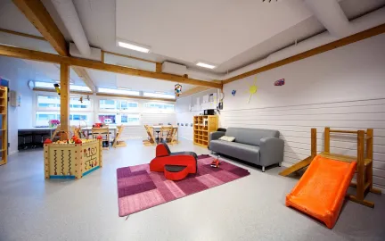 Iinneområde med sofa, bord, lekekasser og sklie i Prestvannet studentbarnehage