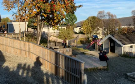 Gimle studentbarnehage med lekeområde sett utenfra en sommerdag med blå himmel