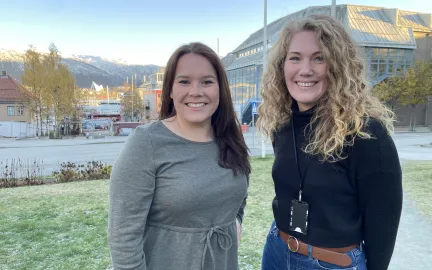 Sigrid Mogård-Jansen, til venstre, og Helga Bårdsdatter Kristiansen fra Tromsø kommune står på plenen utenfor rådhuset, og smiler mot kamera.