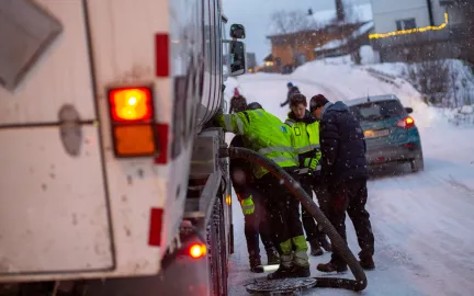Fire arbeidere står over åpen kum midt i gate i Tromsø.