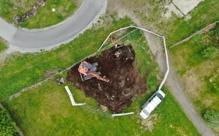 Dronebilde av gravemaskin og grøft i skolegård