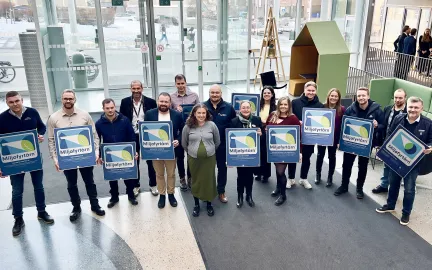 Miljøsertifikatmottakere smiler til kamera i rådhusfoajeen.
