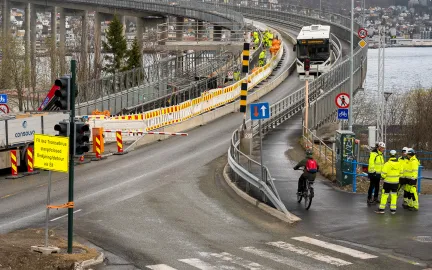 Arbeidere i gule klær jobber i gangveien på Tromsøbrua