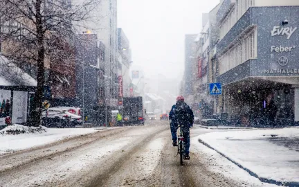 Syklist i bygate i lett snøvær