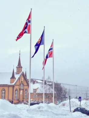 To norske og et kvensk flagg vaier utenfor Tromsø rådhus i mars 2019