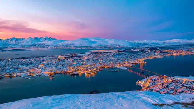 Panoramabilde av et snøkledt Tromsøya tatt fra fjellheisen i Tromsdalen.