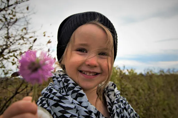 Smilende jente Smilende jente som holder en blomst i hånden