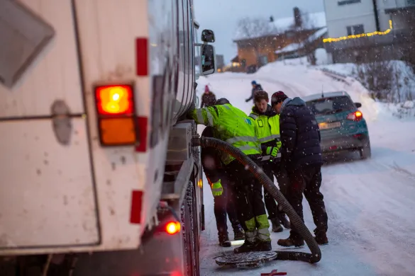 Fire arbeidere står over åpen kum midt i gate i Tromsø.