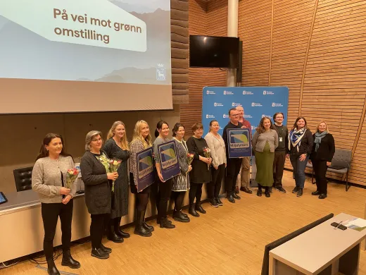 Kommunale mottakere av miljøfyrtårnsertifiseringen 28 februar 2025 i kommunestyresalen Ansatte og ledere i Tromsø kommunen poserer for fotograf med blomster og miljøfyrtårndiplom