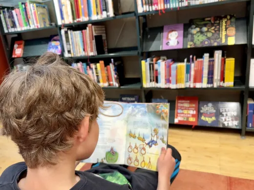 Barn leser bok på bibliotek