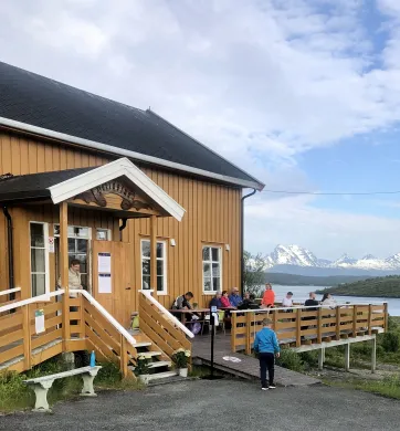Bilde som viser bygningen Bryggeloftet på Hella med fjell og hav i bakgrunnen