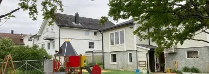Bamsestua friluftsbarnehage uteområde med lekeapparater en grå sommerdag