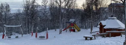 Uteområde med lavvo, husker og leketårn en fin vinterdag med snø og blå himmel