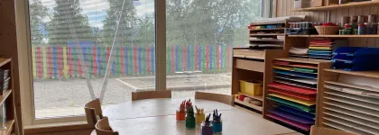 Inneområde i Sjømannsbyen barnehage med formingsrom, sitteområde med fargestifter og hyller med farget papir.