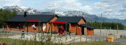 Uteområde på Skittenelv barnehage med sandkasser og husker, blå himmel en solrik sommerdag