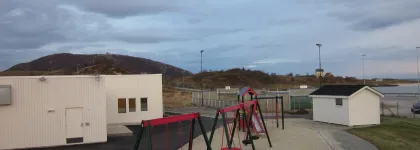 Sommarøy barnehage uteområde med husker og sandkasse en sommerdag