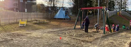 Workinnmarka barnehage uteområde med lavvo, husker og mange barn en solrik sommerdag