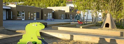 Barnehagen sett utenfra med sandkasser, sklie og lavvo i Norlandia Marsvegen barnehage