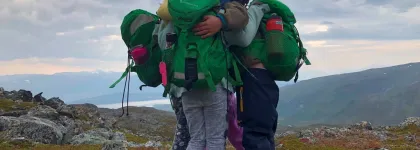 Tre barn holder rundt hverandre på en fjelltopp en tidlig høstdag