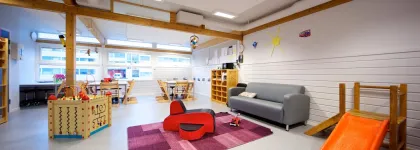 Iinneområde med sofa, bord, lekekasser og sklie i Prestvannet studentbarnehage