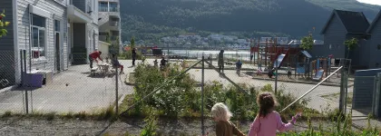 To jenter holder hender og leker i uteområdet i Strandkanten FUS barnehage