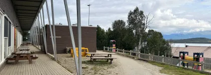 Uteområde med benker og klatretårn en sen sommerdag med skyer og blå himmel.